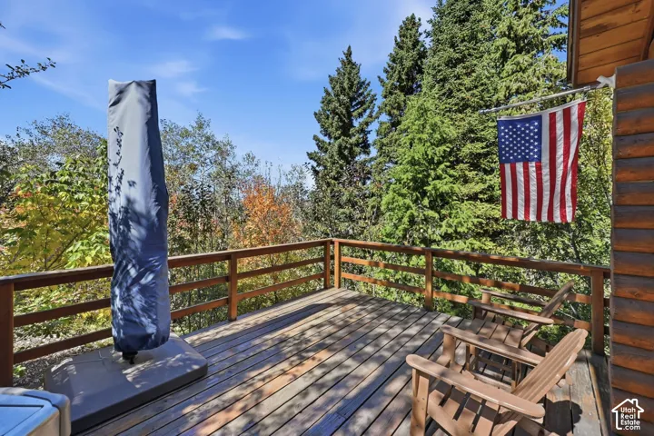 Expansive wood deck with a wood railing, surrounded by mature trees