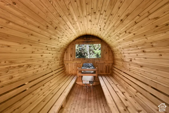 Barrel sauna with light wood paneling, built-in wooden benches, and an integrated sauna heater