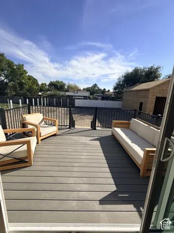 Expansive outdoor deck featuring composite decking, black metal railings, and a direct walk-out to an open yard area