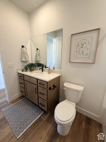 Wood-finish flooring, white walls, and a wood vanity with a white countertop
