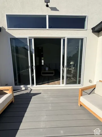 Expansive grey composite decking with white frame sliding glass doors, transom windows, and a stucco exterior