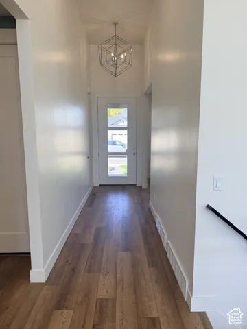 Foyer with wood-finish flooring, a contemporary geometric chandelier, and a white entry door with frosted glass panels
