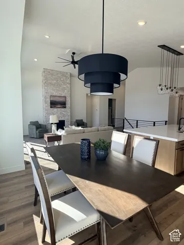 Vaulted ceilings with recessed lighting, stone-clad fireplace, wood-finish flooring, and contemporary light fixtures
