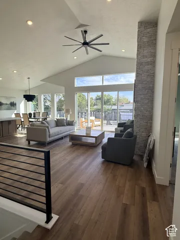 Vaulted ceilings with recessed lighting, wood-finish flooring, a contemporary ceiling fan, and a stone-clad pillar