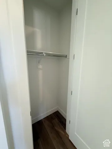 Interior closet featuring a chrome hanging rod and wood-finish flooring