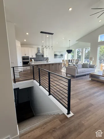 Open-concept living area with vaulted ceilings, recessed lighting, and wood-finish flooring
