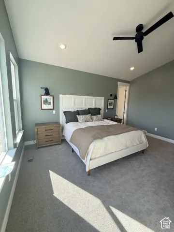 Carpeted room featuring a ceiling fan, recessed lighting, and multiple windows