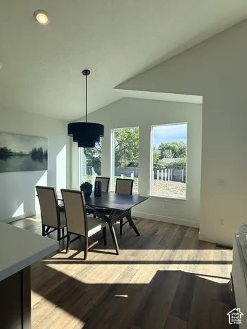 Wood-finish flooring, vaulted ceiling, recessed lighting, and a tiered drum pendant light fixture