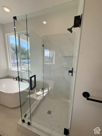 Frameless glass shower enclosure featuring matte black hardware, herringbone tile shower floor, and a built-in shower niche