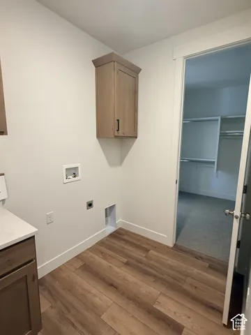 Wood-finish flooring, light-toned cabinetry, built-in wall cabinet, and a white countertop