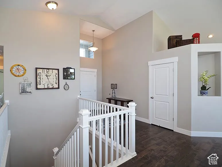 Vaulted ceiling, wood-finish flooring, white painted railing, recessed lighting, and built-in wall niche