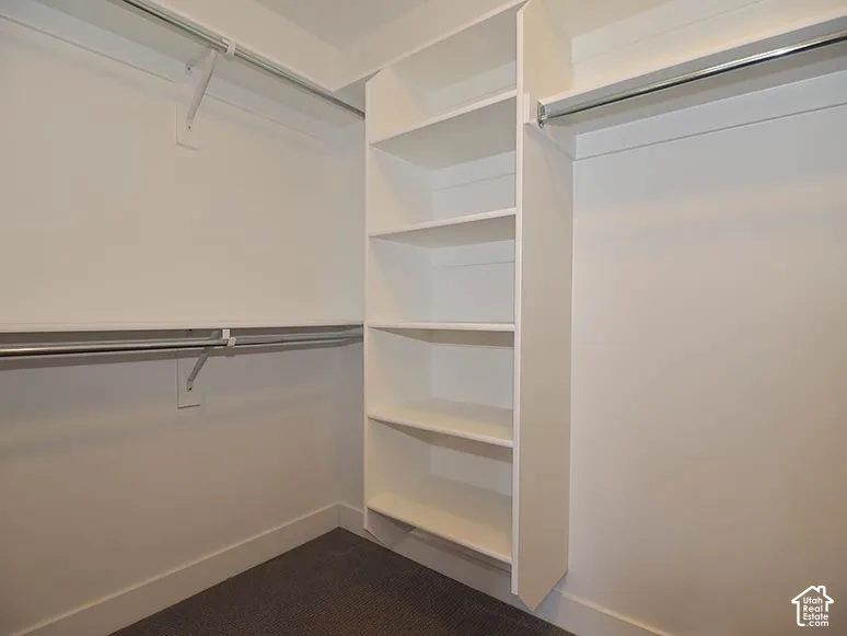 Integrated shelving unit, multiple hanging rods, white walls, and carpet flooring