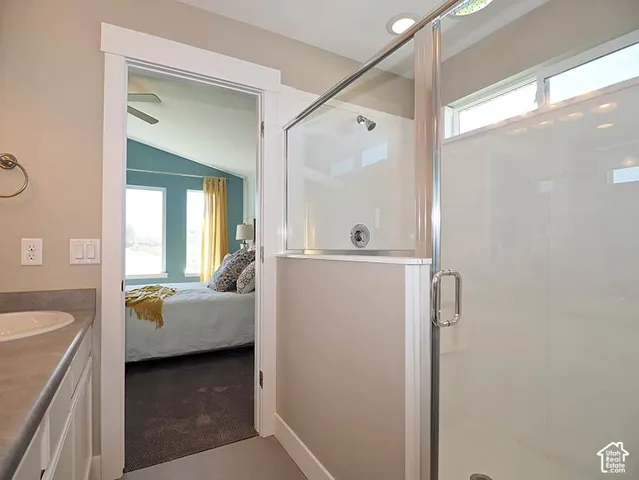 Glass-enclosed shower with a rainfall showerhead, white vanity with integrated sink, and a light-colored countertop