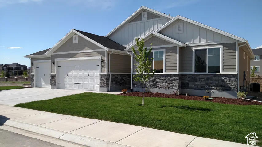 Exterior featuring horizontal siding, stone veneer accents, multiple large windows, and a two-car garage with a separate single-car garage