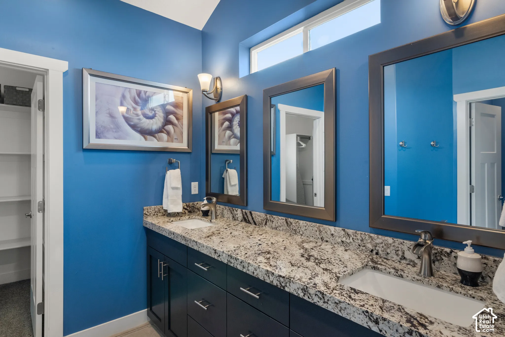Dual undermount sinks with brushed nickel faucets, dark wood-finish vanity with drawer storage, speckled stone-finish countertop, and two framed mirrors