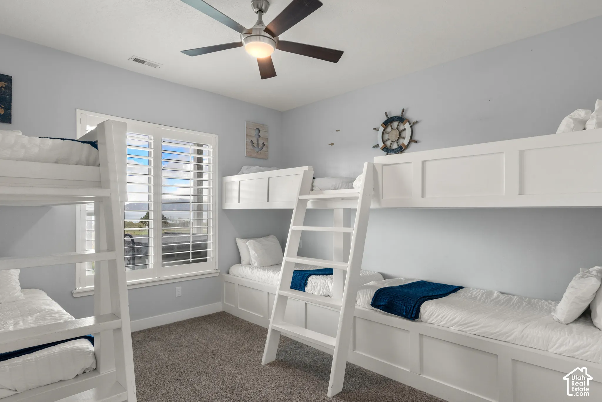 Built-in bunk beds, window with plantation shutters, ceiling fan with integrated lighting, and neutral wall color