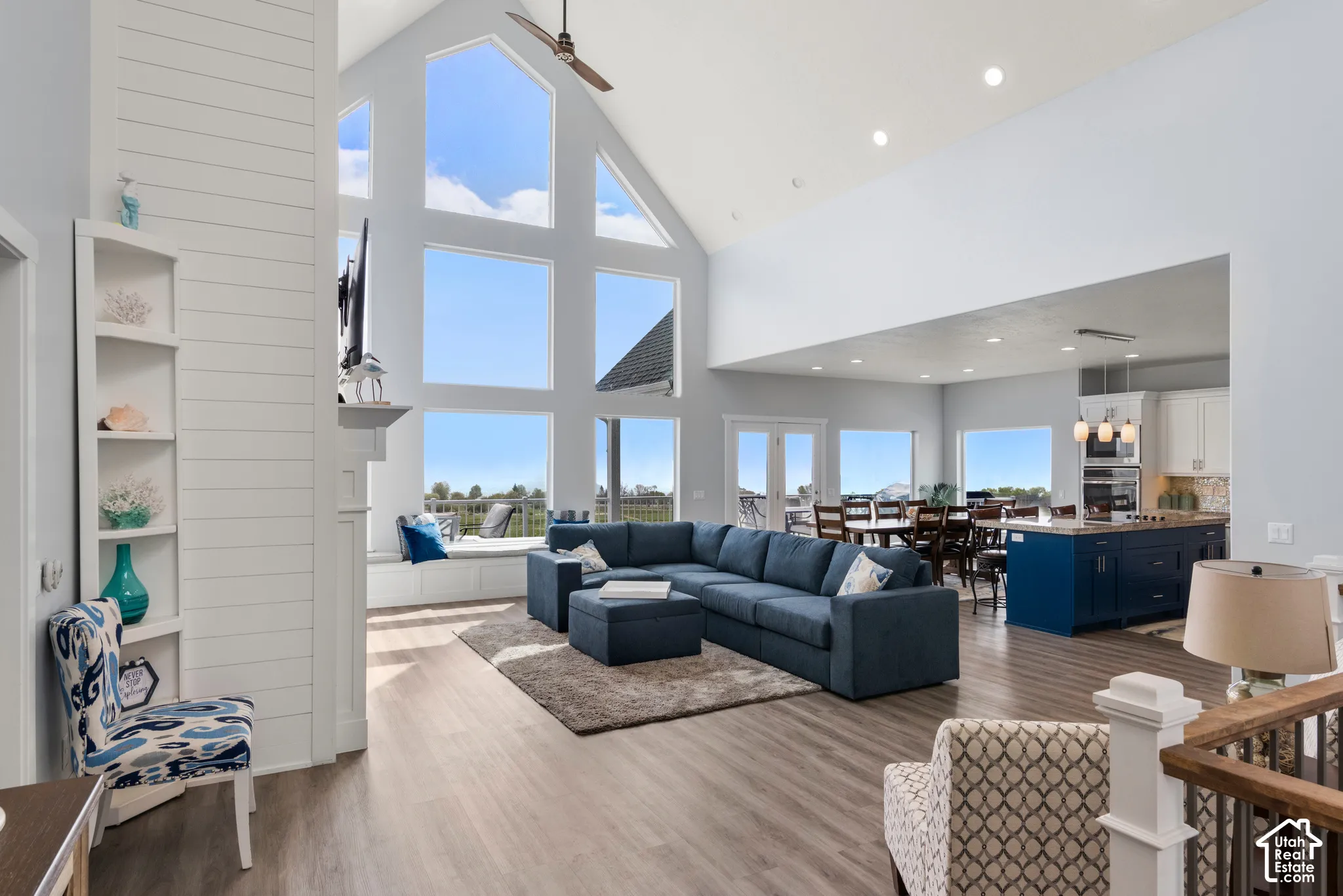 Vaulted ceiling with a ceiling fan, a wall of windows, built-in shelving, wood-finish flooring, and a built-in window seat