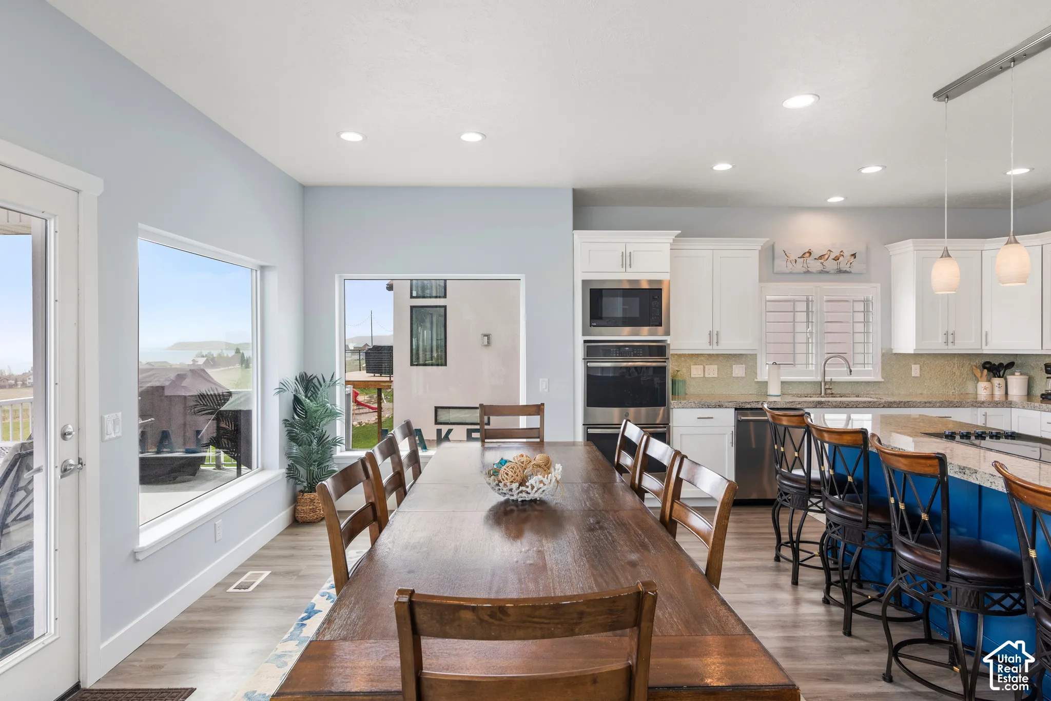 Integrated dining area and kitchen featuring wood-finish flooring, recessed lighting, and white cabinetry