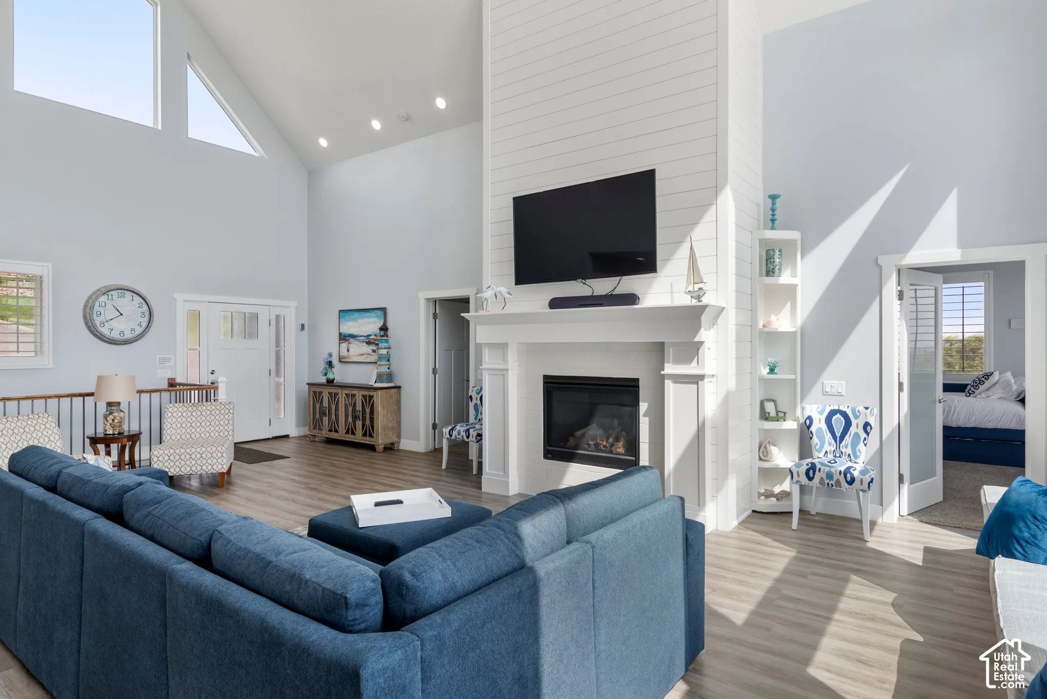 Vaulted ceiling, wood-finish flooring, white shiplap fireplace surround, built-in fireplace, and transom windows