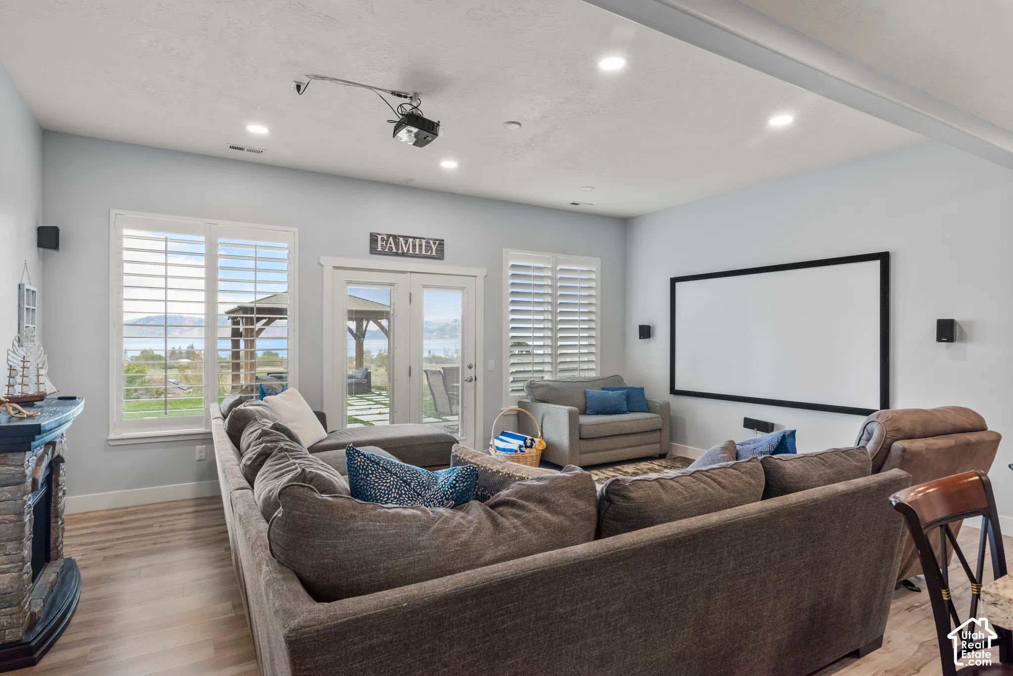 Recessed lighting, wood-finish flooring, white plantation shutters, built-in projector screen, and direct outdoor access