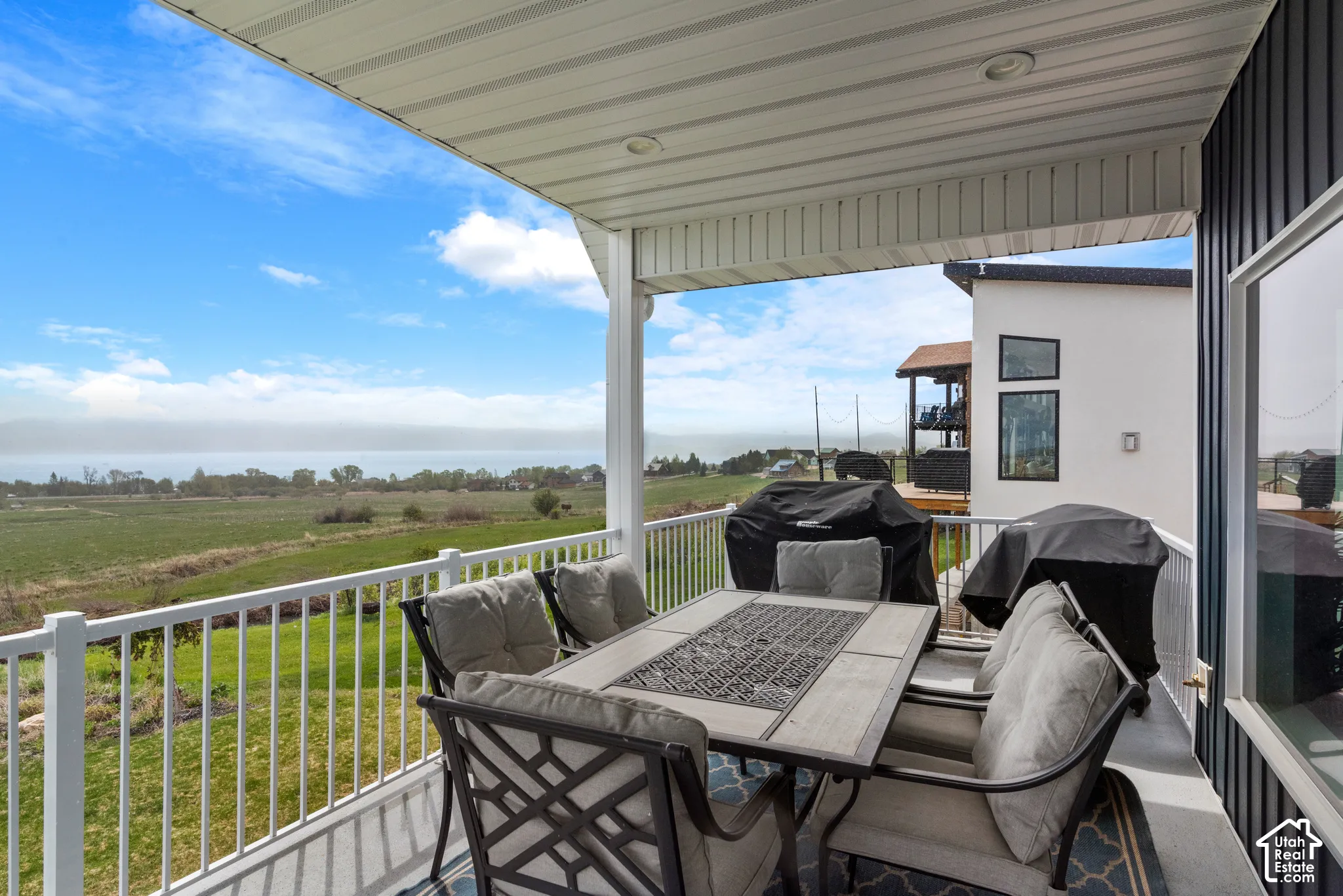 Covered outdoor deck with white railing, corrugated ceiling, and recessed lighting