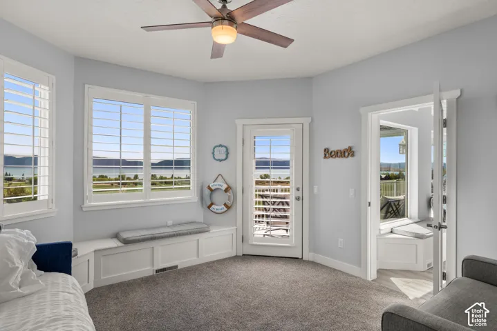 Carpeted room with a ceiling fan, white plantation shutters, and a built-in window bench