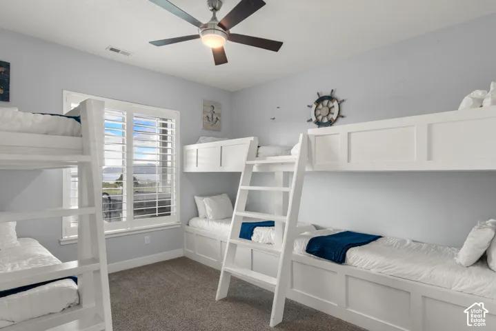 Built-in bunk beds, window with plantation shutters, ceiling fan with integrated lighting, and neutral wall color
