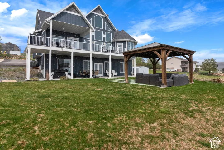 Multi-level dwelling with a gable roof, two expansive balconies with white railings, and a lower-level patio