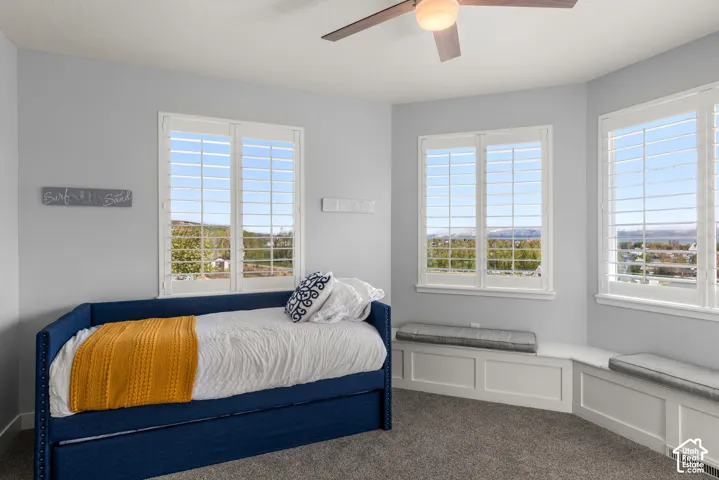 Multiple windows with white plantation shutters, built-in window seating, and a ceiling fan with integrated lighting