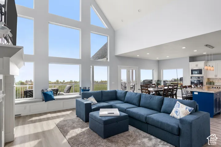 Vaulted ceiling living area with expansive window wall, wood-finish flooring, and a built-in window bench