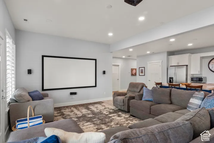 Open-concept living space featuring a built-in projector screen, recessed lighting, and wood-finish flooring