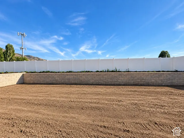 Property perimeter featuring a white privacy fence and retaining walls