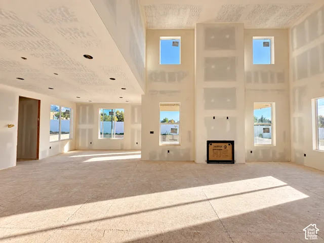 Spacious room with a two-story ceiling, multiple windows, recessed ceiling lighting, and a built-in fireplace