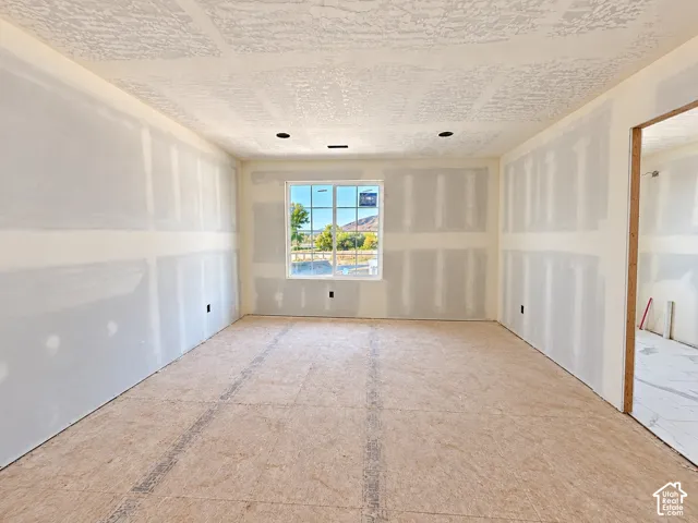 Spacious room featuring a large window, recessed lighting, and a textured ceiling