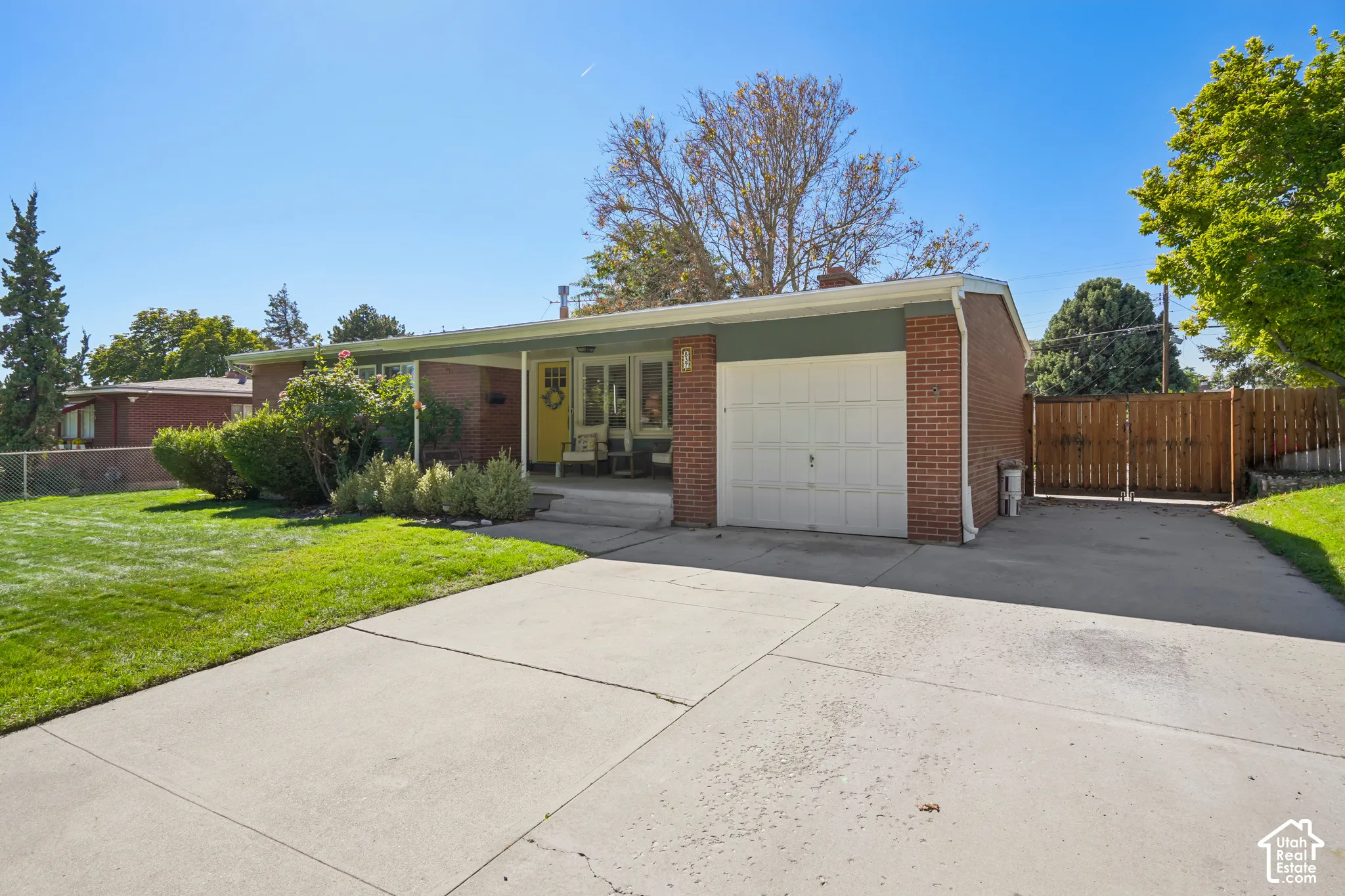 Brick exterior with an attached garage, covered entryway, and a paved driveway