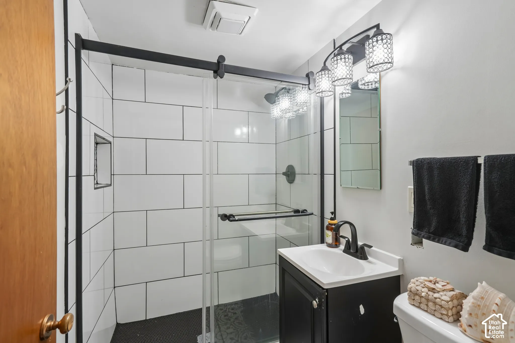 Shower featuring subway tile surround, black-framed sliding glass door, and integrated niche