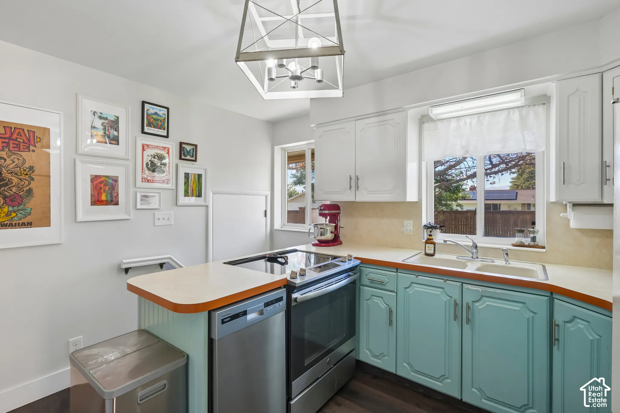 Kitchen featuring white upper cabinetry, teal lower cabinetry, and a double basin sink