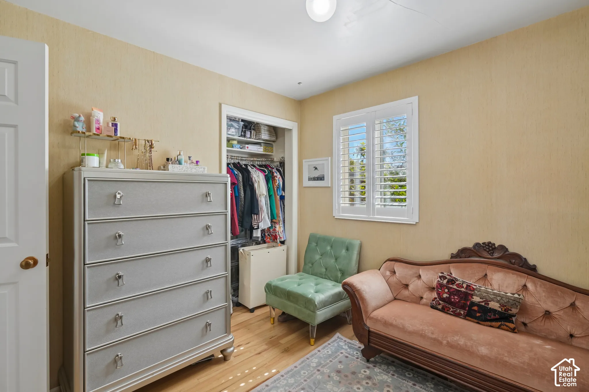 Hardwood-style flooring, white window shutters, and a built-in closet with shelving