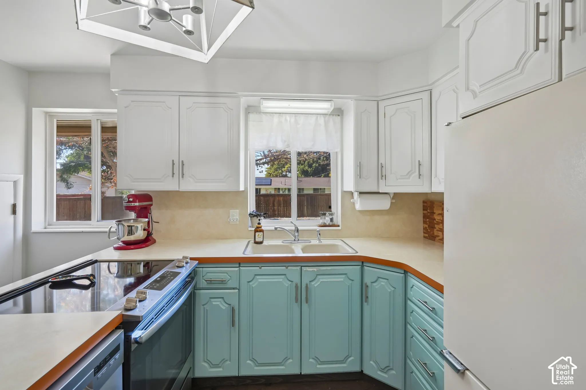 Kitchen featuring white upper cabinetry, teal lower cabinetry, a built-in electric range, a double basin sink, and wood-finish flooring