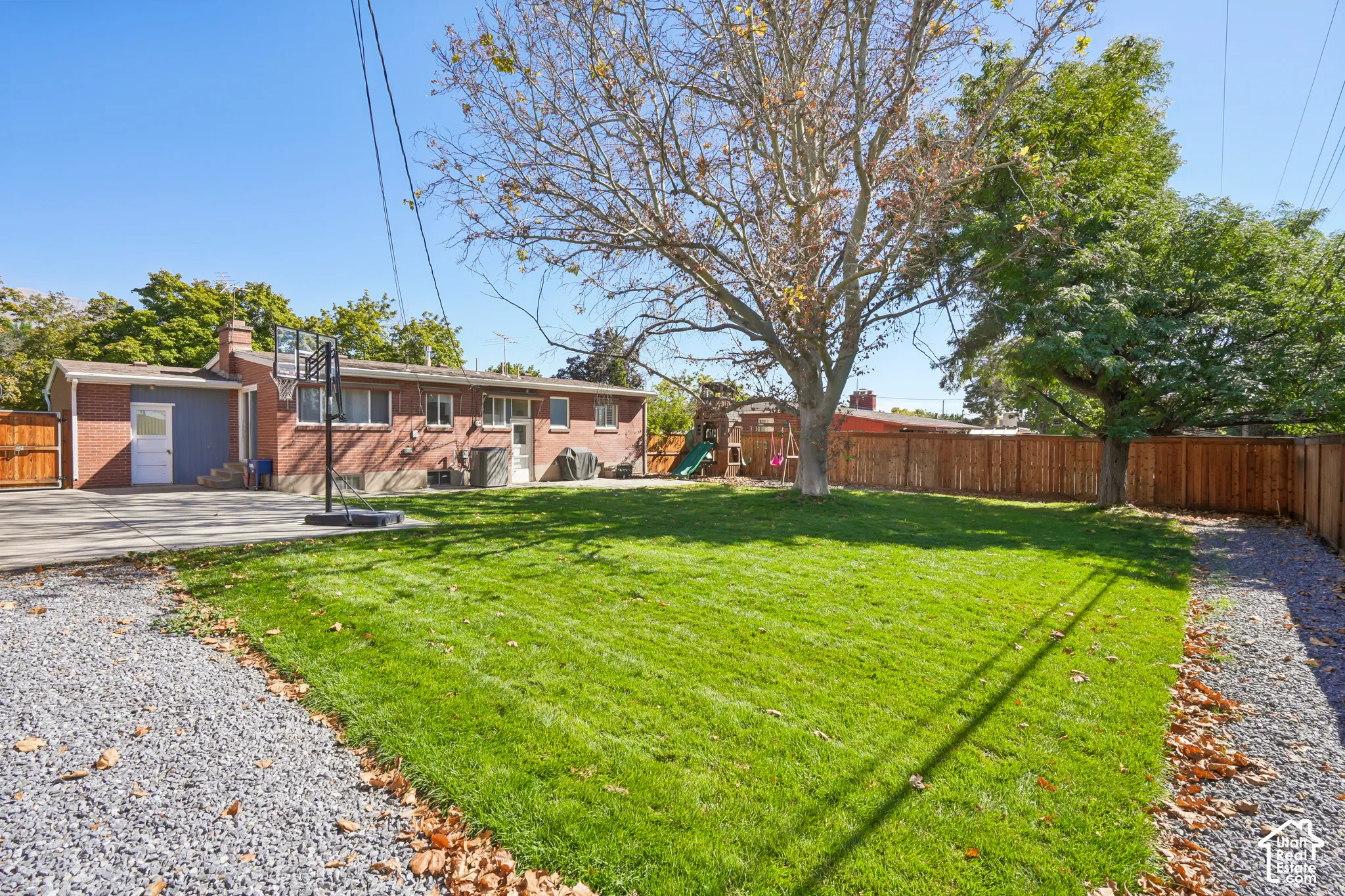 Expansive backyard featuring a manicured lawn, established trees, and a full privacy fence