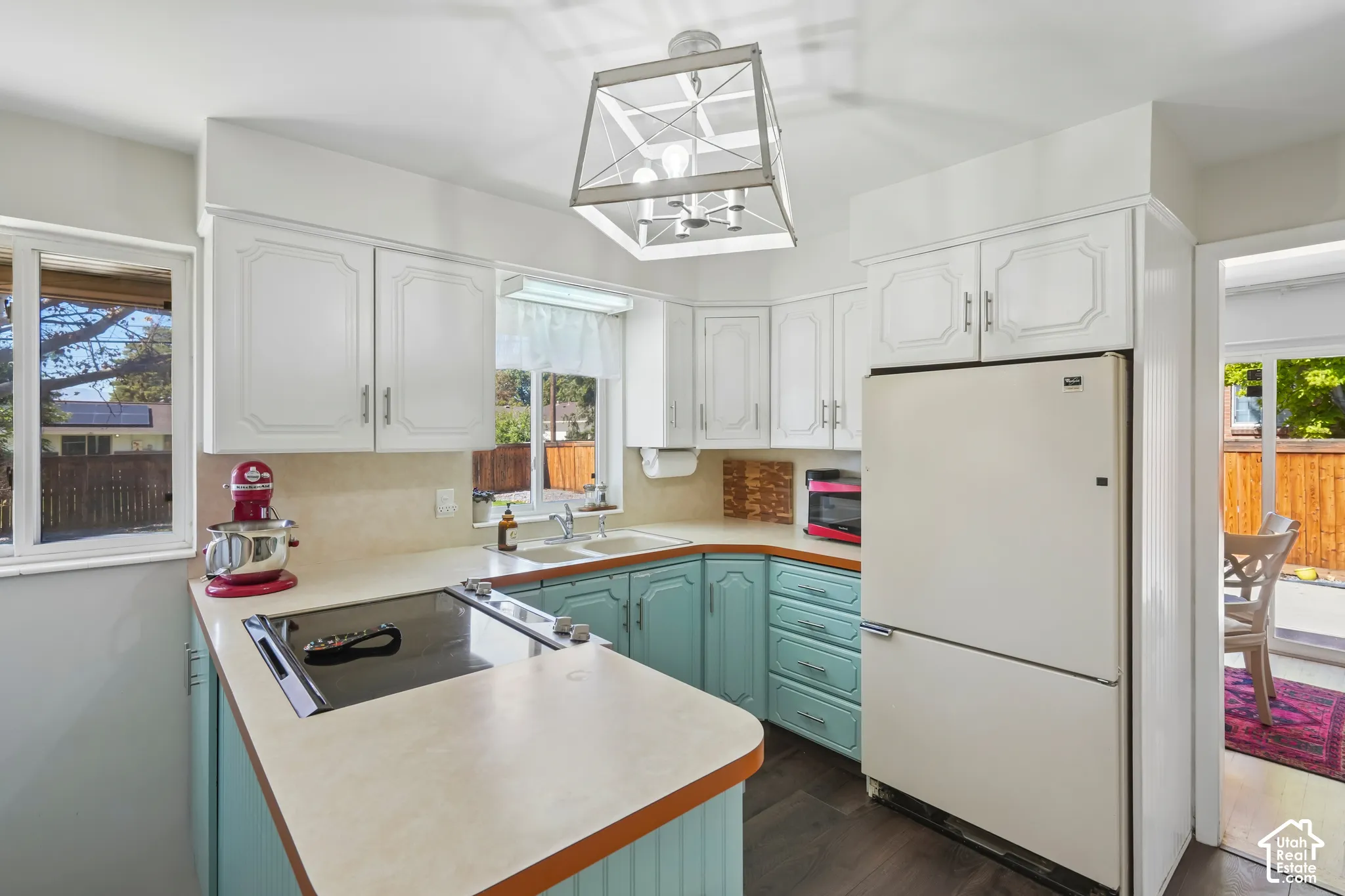 Kitchen featuring white upper cabinetry, teal lower cabinetry, a built-in electric cooktop, and a double basin sink