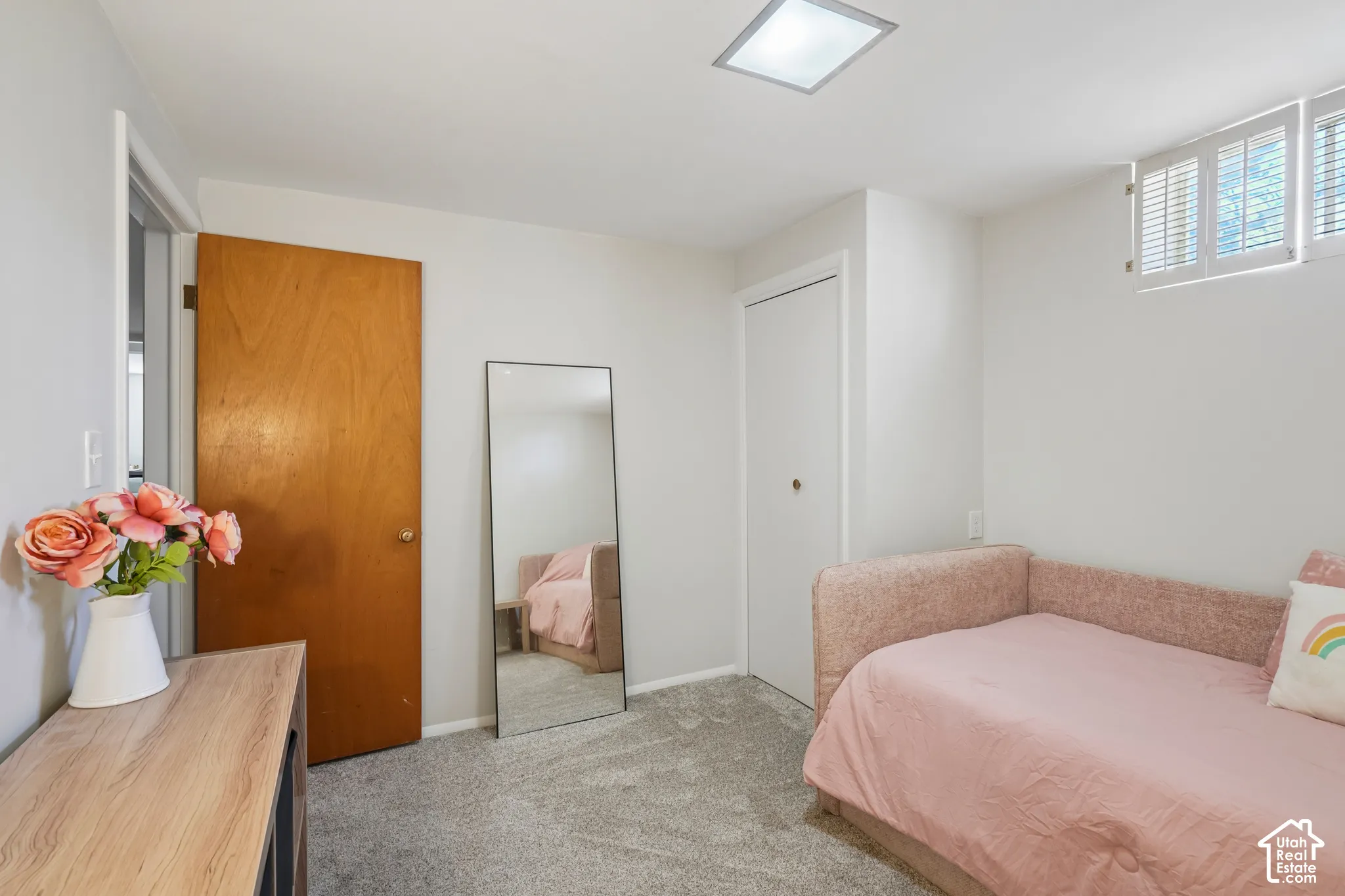 Wall-to-wall carpeting, wood-finish door, white walls, flush-mount ceiling light, window with shutters