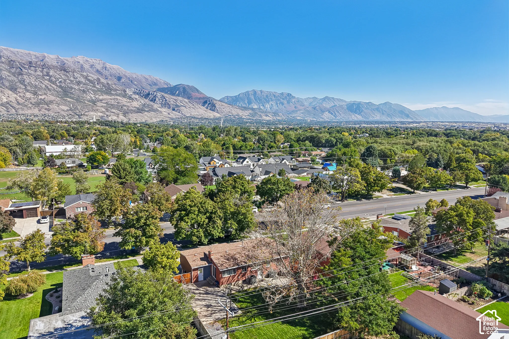 Mountain range backdrop, residential area, mature trees, paved streets, clear sky