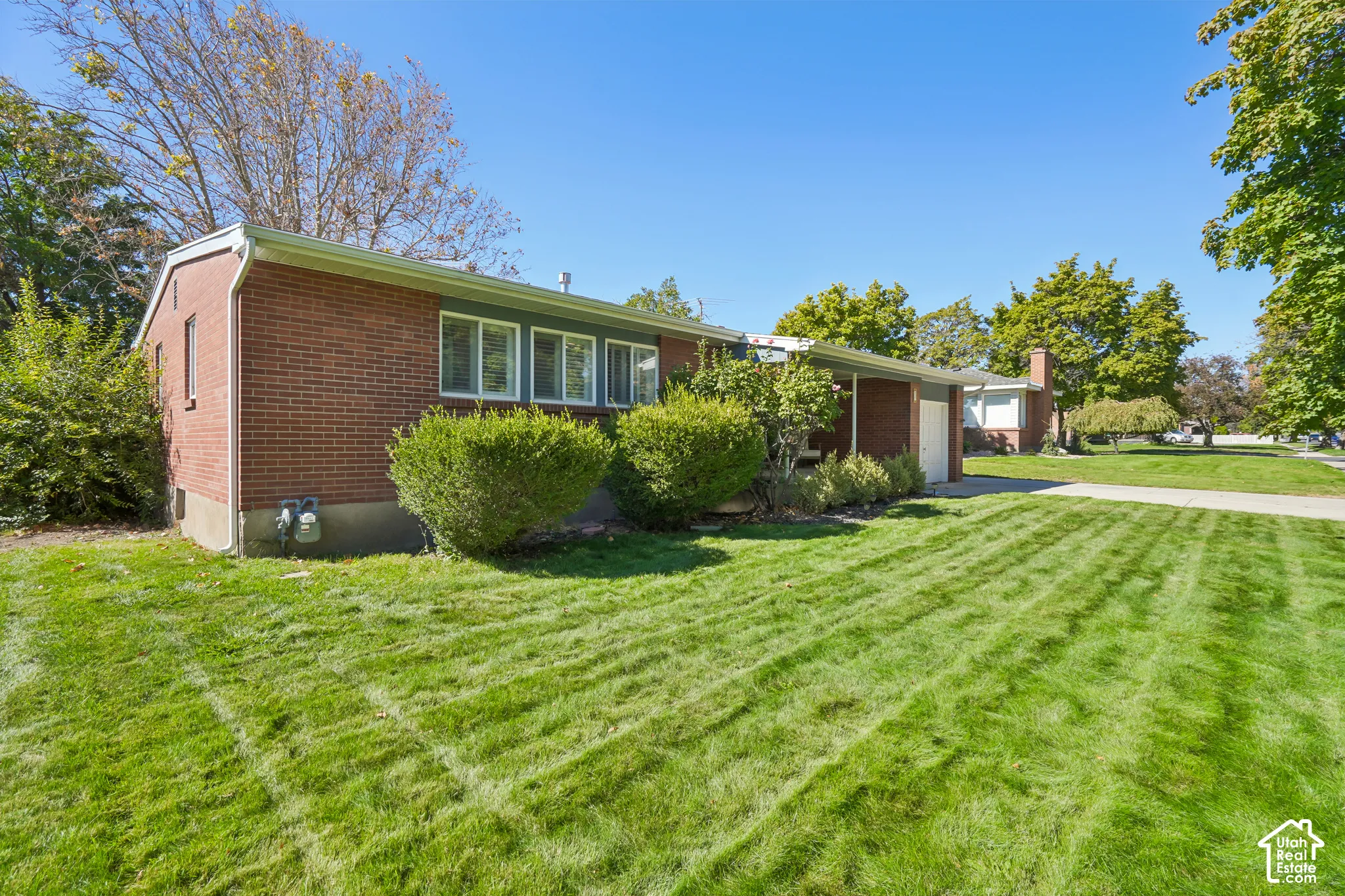 Brick exterior with white-framed windows, green trim, and established landscaping