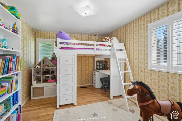 Wood-finish flooring, white built-in shelving, white window shutters, and a flush mount ceiling light