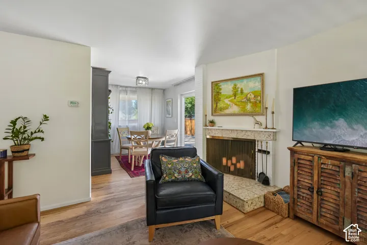 Living area featuring wood-finish flooring, a fireplace with a stone mantel, and a dining area with direct exterior access