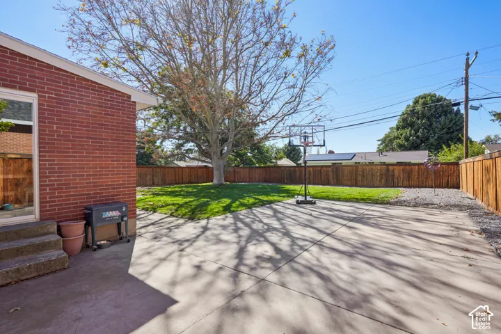 Expansive backyard featuring a manicured lawn, concrete patio, and privacy fencing