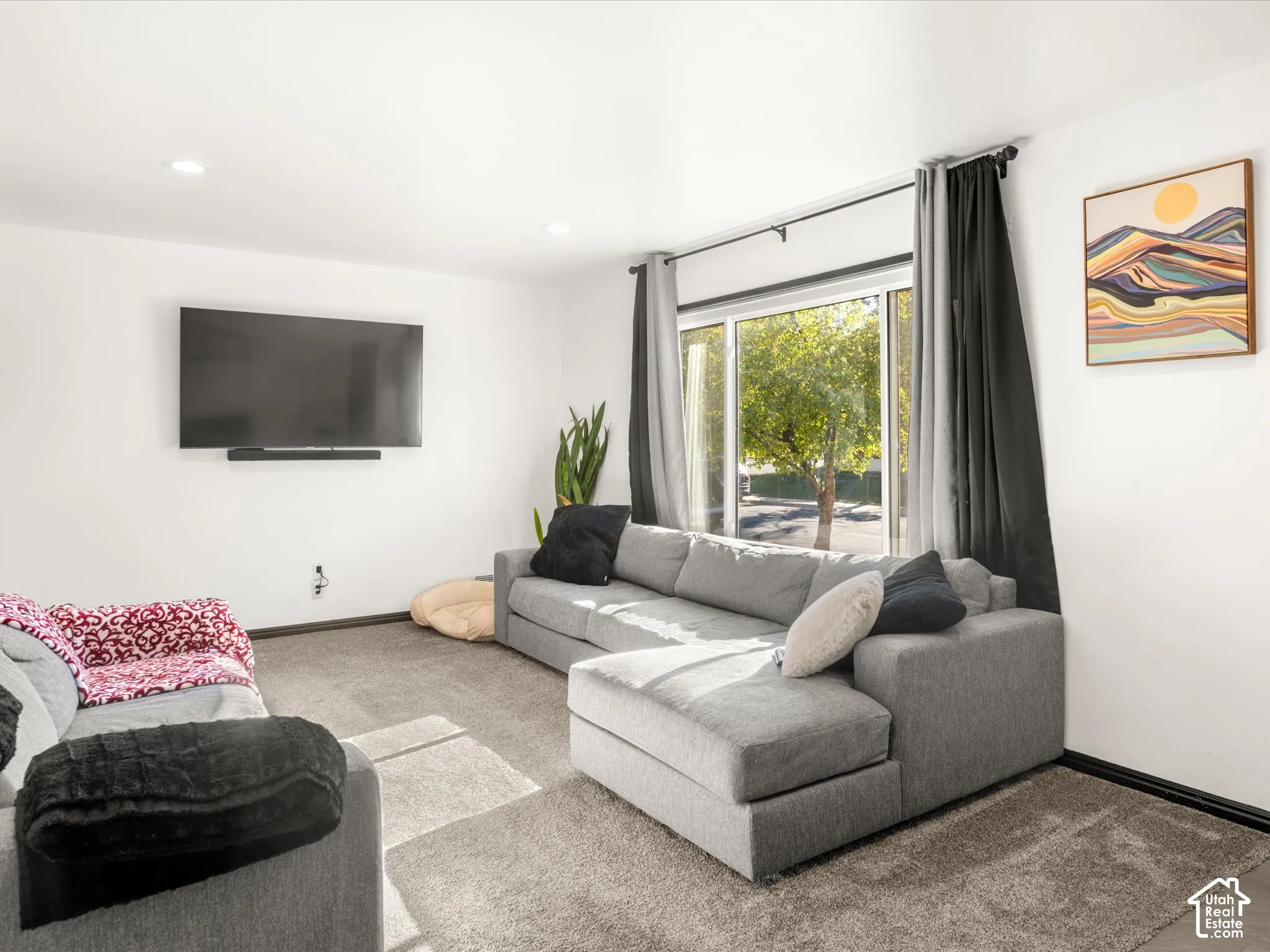Recessed ceiling lighting, wall-mounted television, and a sliding glass door with a dark rod and drapery