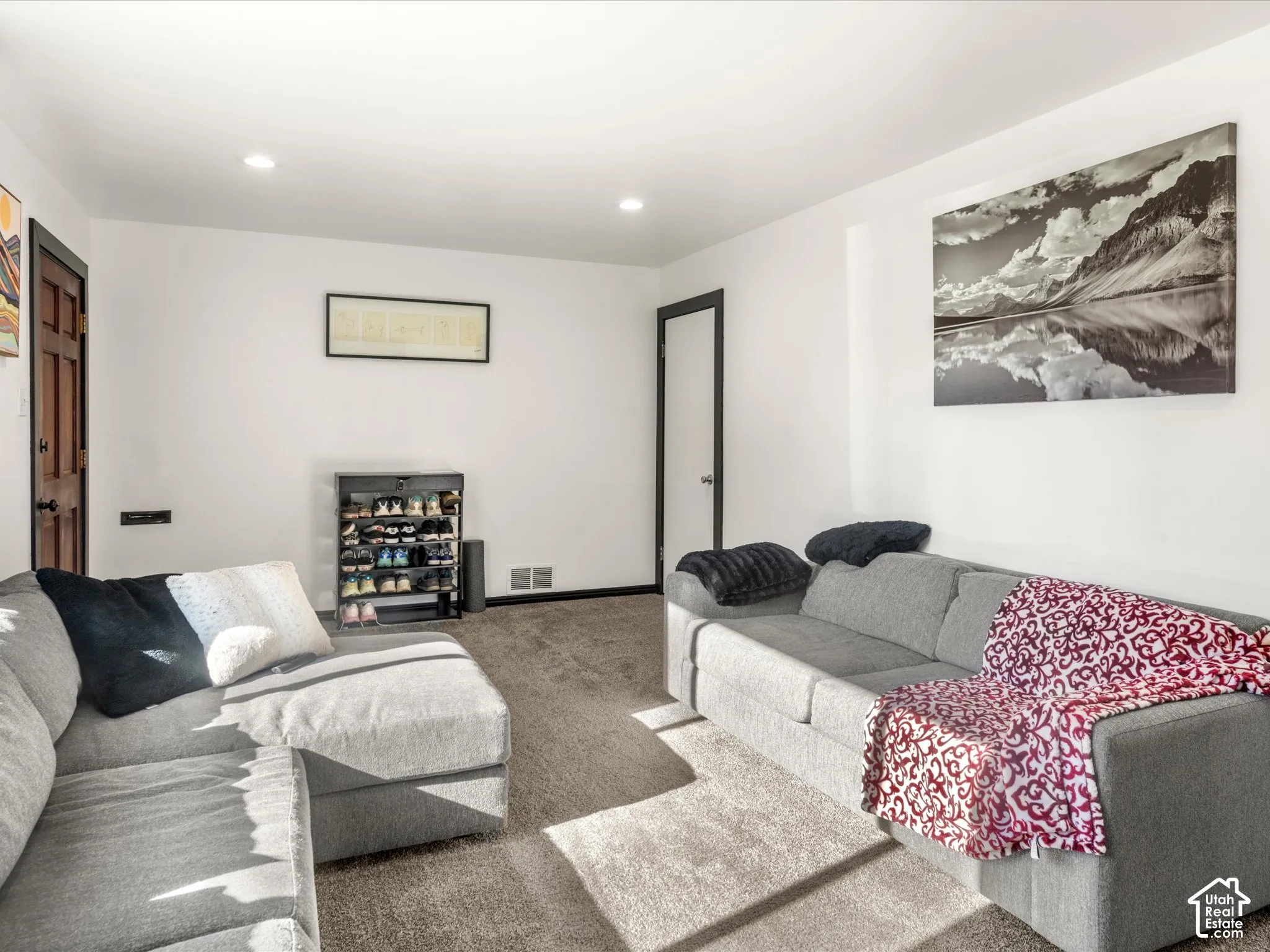 Recessed lighting illuminates neutral carpeting and white walls