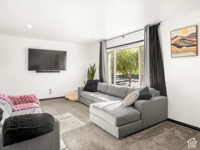 Recessed ceiling lighting, wall-mounted television, and a sliding glass door with a dark rod and drapery